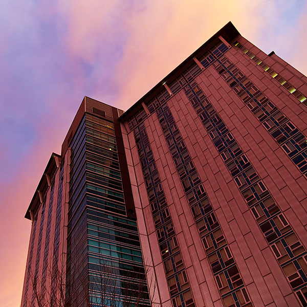 A modern high-rise building against a colorful sunset sky.