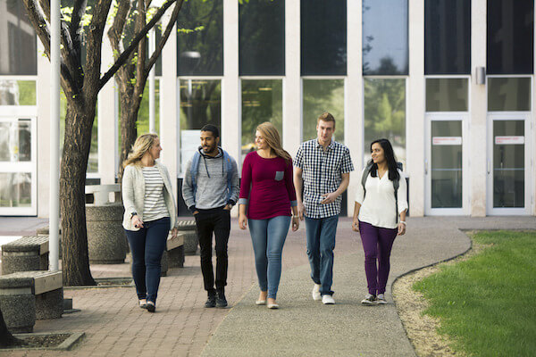 Group of students walk side-by-side outside the Senator Burns Building. 