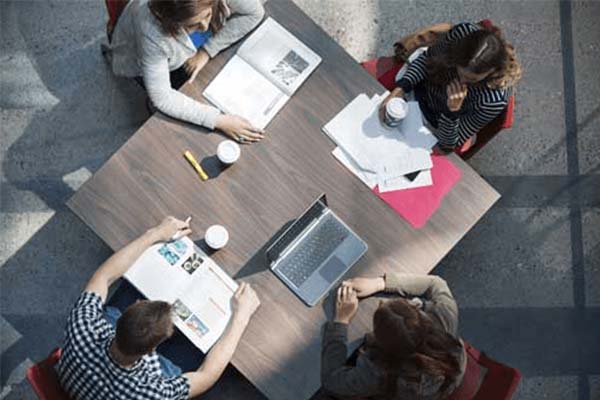 A group of students studying at a table, as seen from above.