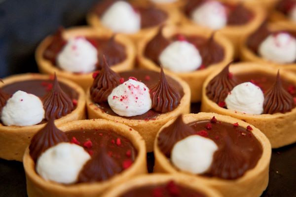 Delicious chocolate tartlets topped with whipped cream and raspberry sprinkles.