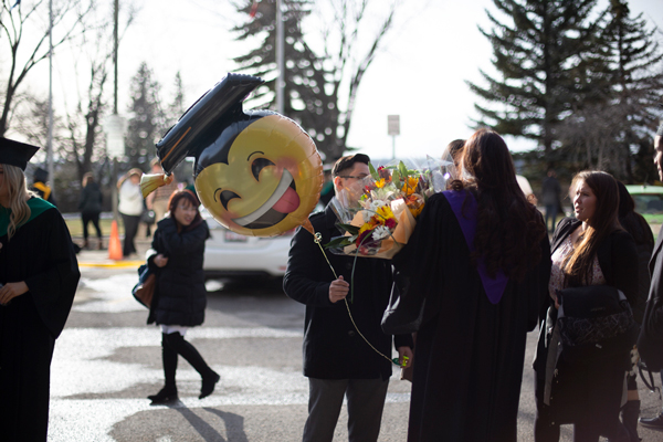 student in a graduation gown holding a balloon