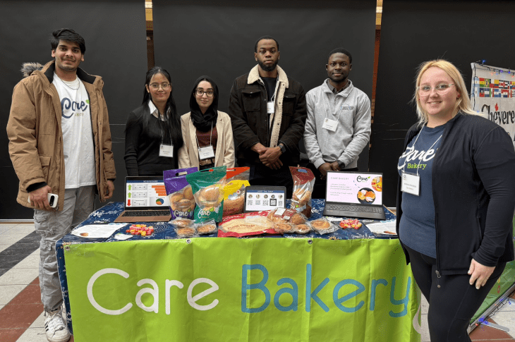Students stand at a capstone project booth for Care Bakery.