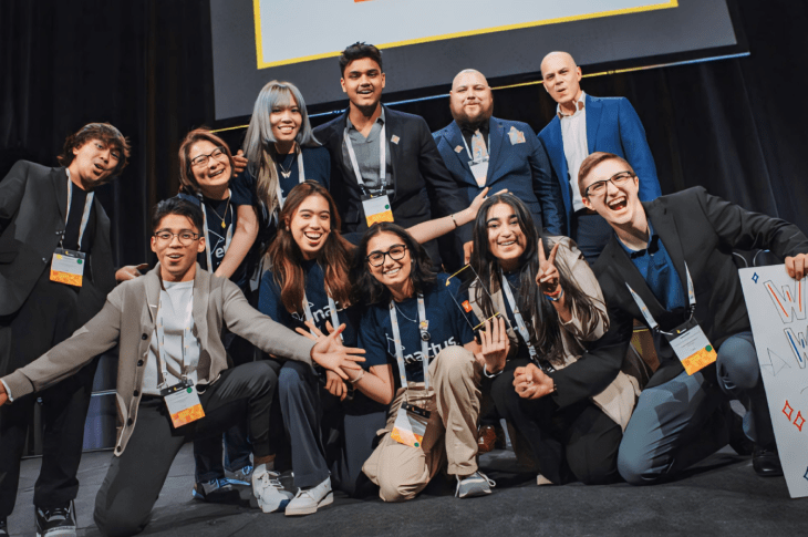 Students huddle together for a group photo at an Enactus event.